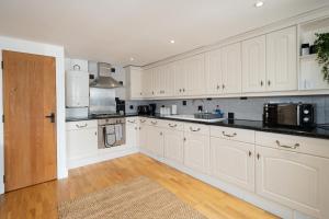 a large white kitchen with white cabinets and a door at Beautiful 3BR Home Close to Town Centre in Kent