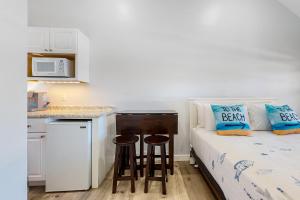 een kleine slaapkamer met een bed en een kleine keuken bij Beach Pleasure in Hampton