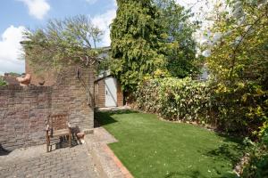 Beautiful 3BR Home Close to Town Centre في Kent: حديقة مع مقعد بجوار جدار من الطوب