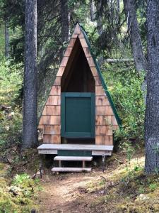a dog house with a green door in the woods at Vines and Puppies Glamping Hideaway in Jade City