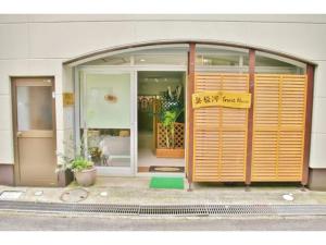 un front de magasin avec un panneau devant lui dans l'établissement Okusuruga Guest House - Vacation STAY 14698, à Numazu