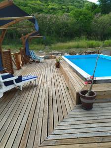 une terrasse en bois avec une piscine et des chaises dans l'établissement Aichi lodges gîtes, à Capesterre