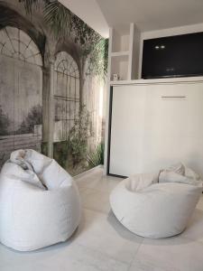 two white bean chairs in a room with a screen at AL PONTE design apartment in Conegliano