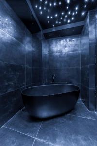 a black bath tub in a bathroom with stars on the ceiling at Kennedy Residence Belgrade in Belgrade