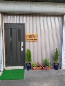 Guest House Tatara - Vacation STAY 61943v في Yasugi: باب لمبنى فيه نباتات الفخار