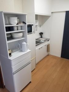 Guest House Tatara - Vacation STAY 61943v في Yasugi: مطبخ صغير مع دواليب بيضاء وميكرويف