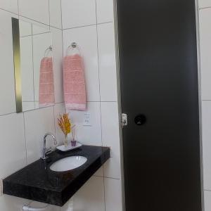 a bathroom with a sink and a mirror and pink towels at Pousada Diadorim in Sao Domingos de Goias