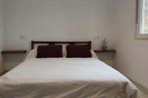 um quarto com uma grande cama branca e 2 almofadas em CASA INDEPENDIENTE SUANCES - 800m2 de jardín - Parking - Wifi5G em Cortiguera