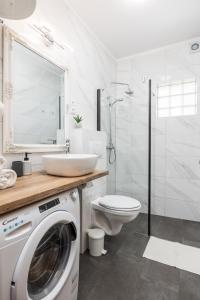 een witte badkamer met een wasmachine bij Apartments More in Klenovica +53 foto's