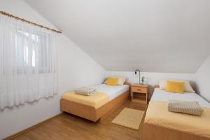 een witte kamer met 2 bedden en een raam bij Apartments More in Klenovica