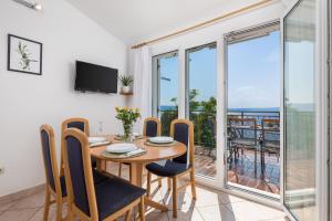 een eetkamer met een tafel en stoelen en een balkon bij Apartments More in Klenovica
