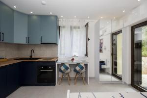 kuchnia z niebieskimi szafkami, zlewem i 2 stołkami w obiekcie Studio Apartments Summer Time w mieście Kamenari