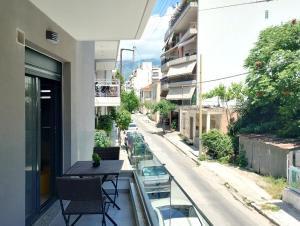 Un balcón con una mesa y sillas y una calle. en Volos Terra Deluxe Residences, en Volos