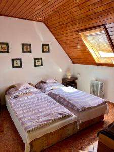 two beds in a room with a roof at Orosz Apartmanház Gyula in Gyula
