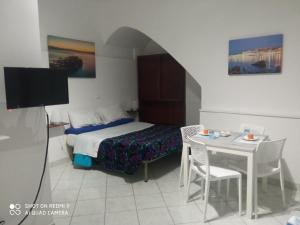 ein Hotelzimmer mit einem Bett, einem Tisch und einem TV in der Unterkunft Al Vicolo in Gaeta