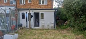 a white shed with three chairs in a yard at Stylish Home from Home in Orpington