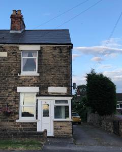 ein Backsteinhaus mit einer weißen Tür und einem weißen Fenster in der Unterkunft Hilltop Cottage in Renishaw