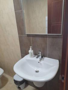 een badkamer met een wastafel, een toilet en een spiegel bij Atico Finisterre in Fisterra