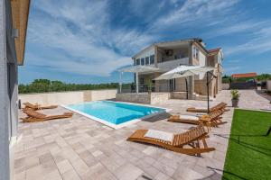 uma piscina com cadeiras e uma casa em Villa bazen,jacuzzy em Sukošan