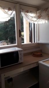 a kitchen with a microwave on a counter next to two windows at B&B Villa Damiano in Copertino