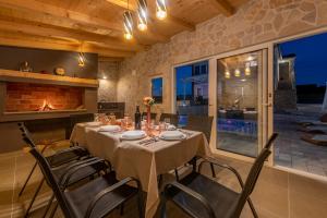uma sala de jantar com uma mesa com cadeiras e uma lareira em Villa bazen,jacuzzy em Sukošan
