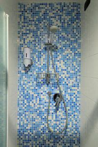 y baño con ducha y pared de azulejos azules. en Dimora del Viaggiatore, en Prato