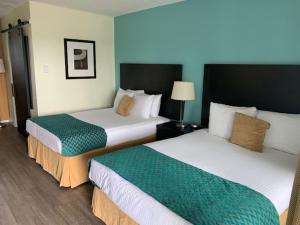 a hotel room with two beds with green and white at Shores Inn & Hotel in Shediac