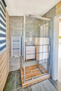 La salle de bains est pourvue d'une douche en verre et d'un lavabo. dans l'établissement Oaza, à Gołubie