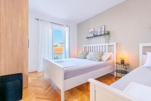 um quarto branco com uma cama e uma janela em Apartmani Zora em Makarska