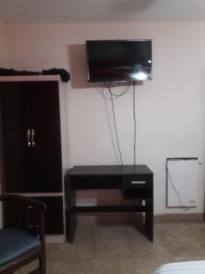 Habitación con tocador negro y TV en la pared. en Habitaciones BRISA, en Salta
