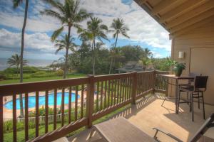 a balcony with a view of a pool and palm trees at Oceanfront 1 BR Condo at Kaha Lani KL309 in Kapaa