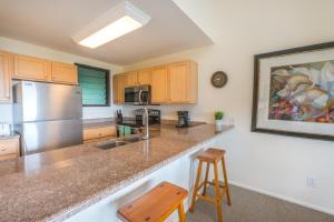 a kitchen with stainless steel appliances and wooden cabinets at Oceanfront 1 BR Condo at Kaha Lani KL309 in Kapaa +12 photos