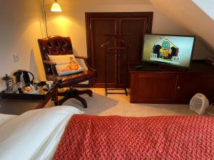 a bedroom with a bed and a chair and a television at Ramadale Stornoway in Stornoway +14 photos