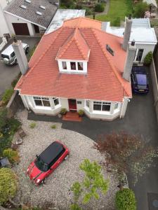 a red roofed house with a red car parked in a driveway at Ramadale B&B in Stornoway