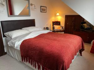 a bedroom with a bed with a red blanket on it at Ramadale Stornoway in Stornoway