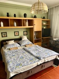 a bedroom with a large bed with a blue comforter at Hajnalka Apartmanház in Gyula