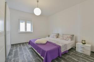 a white bedroom with a purple blanket on a bed at Holiday homEna with a heated pool in Bibinje