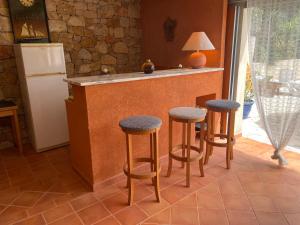 a kitchen with a counter with stools and a refrigerator at VILLA CAU B&B - Les Anglores in Claviers