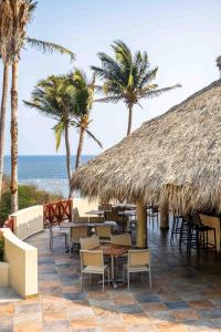 un restaurant avec des chaises, des tables et des palmiers dans l'établissement Villas Coral Huatulco, à Santa Cruz Huatulco