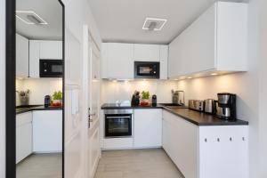 a white kitchen with white cabinets and appliances at Strandwärts in List