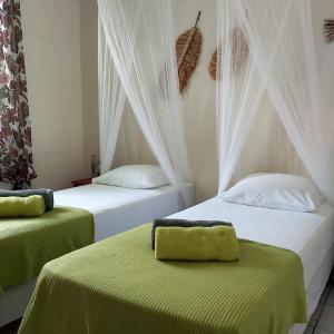 a bedroom with two beds with green sheets at Logisrev in Sainte-Anne