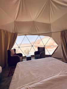 a bedroom with two chairs and a bed in a tent at Wadi rum eagle Luxury camp in Wadi Rum