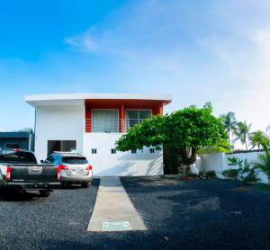 a white house with a car parked in a parking lot at KaiBlue Hotel y Restaurante in La Libertad
