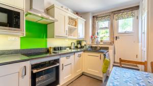 a kitchen with white cabinets and green accents at Rose Cottage in Youlgreave