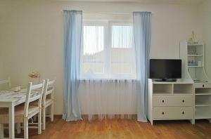 uma sala de estar com uma mesa e uma janela com cortinas azuis em Jediný domček Veľký Meder em Veľký Meder