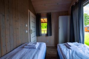 two beds in a room with a window at Kwiatkowo - całoroczny kompleks z baliami i letnią plażą in Wünschelburg