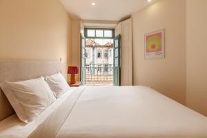 - une chambre avec un grand lit blanc et une fenêtre dans l'établissement Dasi House, à Porto