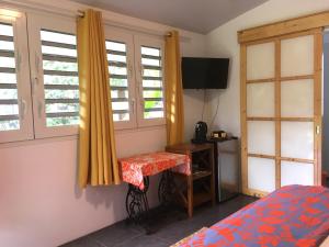 um quarto com uma cama, uma mesa e janelas em TAHITI - Bungalow Honey Moon em Pirae