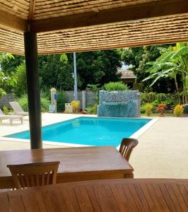 uma mesa e cadeiras em frente a uma piscina em TAHITI - Bungalow Honey Moon em Pirae