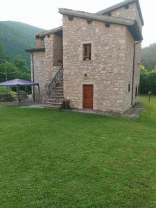 a stone building with a door and a grass yard at La Casa Dei Fagiani in Foligno